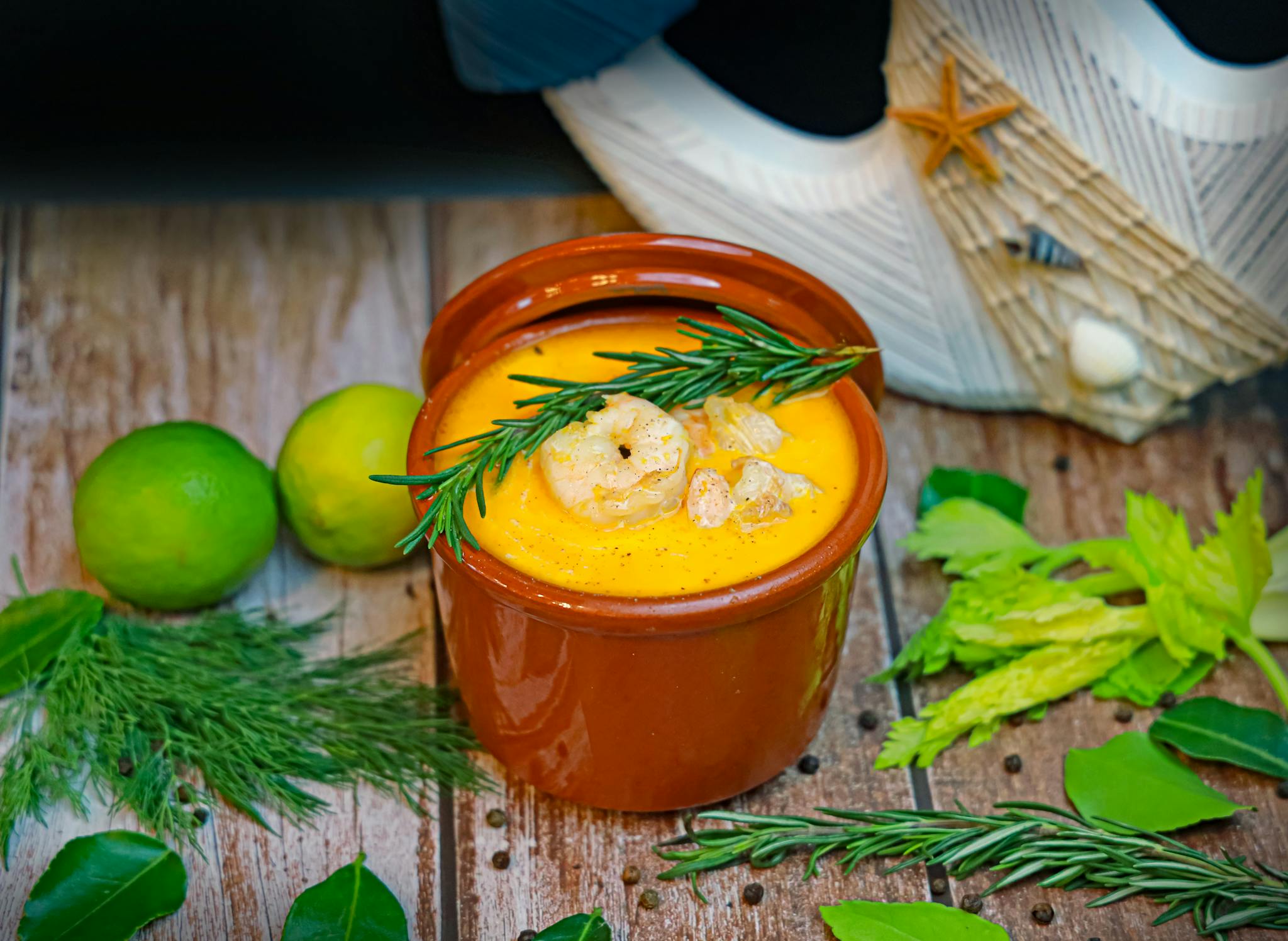 A vibrant seafood soup garnished with rosemary and lime, perfect for a cozy meal.